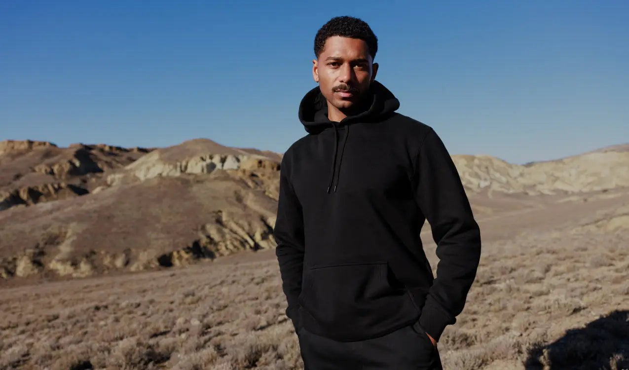 Man in a plain black hoodie showcasing quality design and color in uniforms