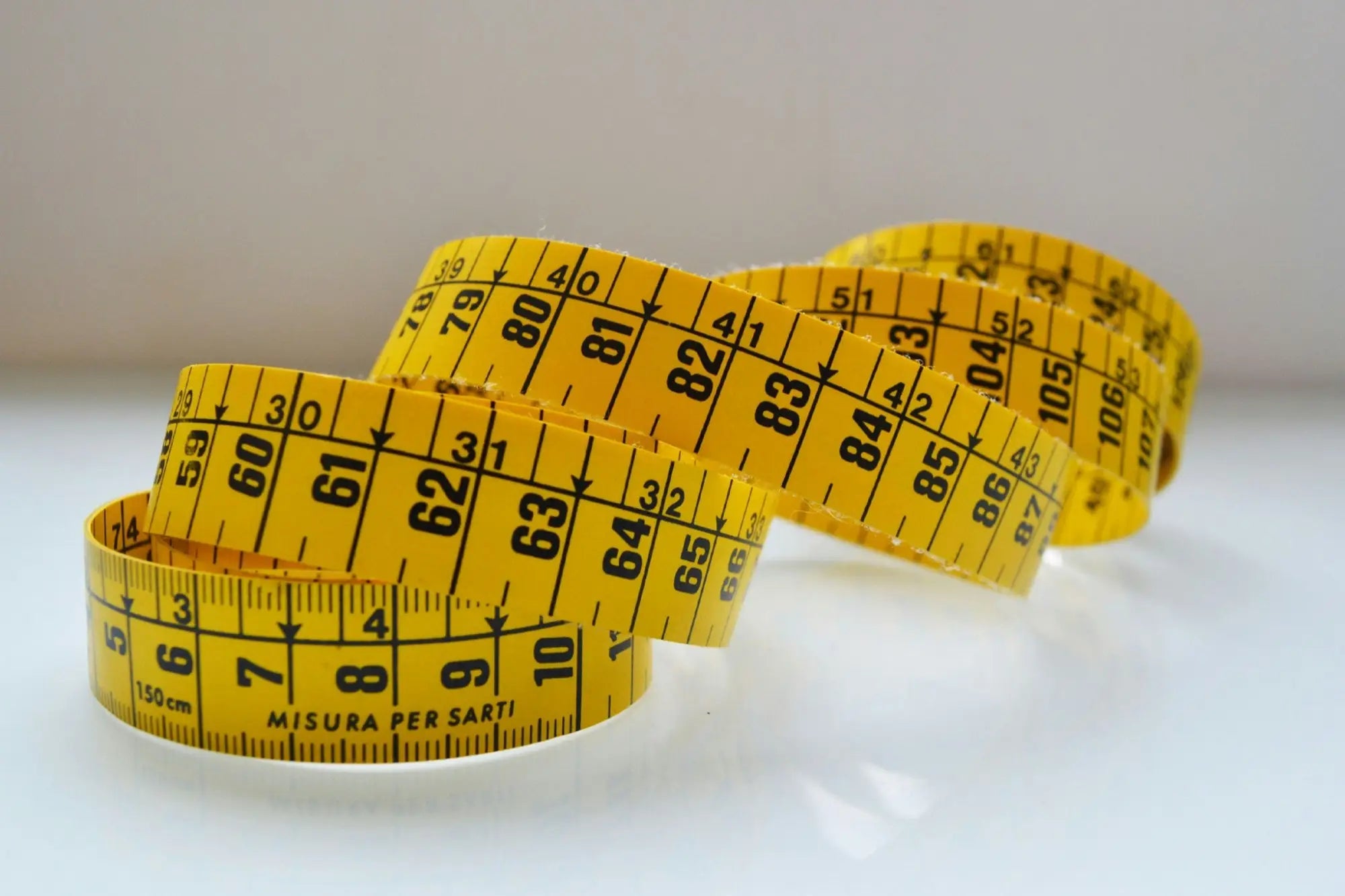 Yellow flexible measuring tape with black markings for half chest measurement on a shirt