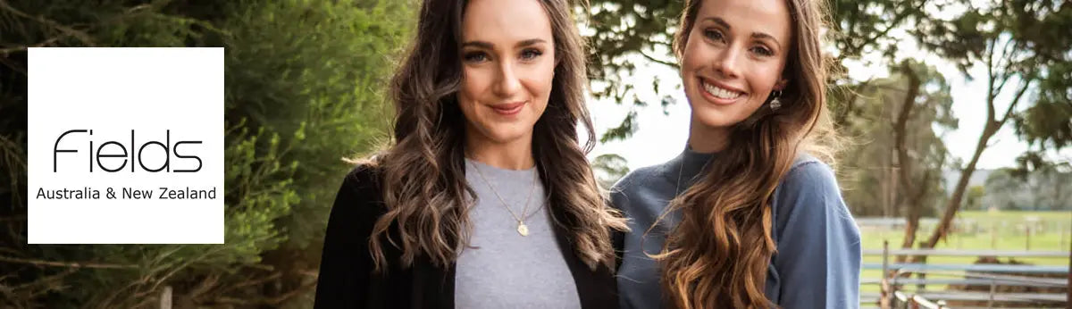 Two smiling women with long wavy brown hair wearing MTF Knitwear corporate pullovers