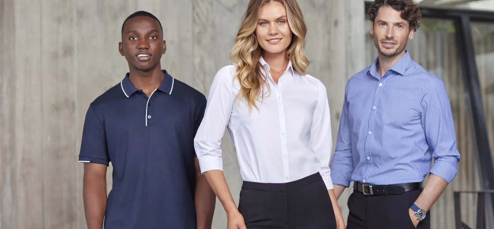 Three people in business attire showcasing hospitality uniforms and industrial workwear