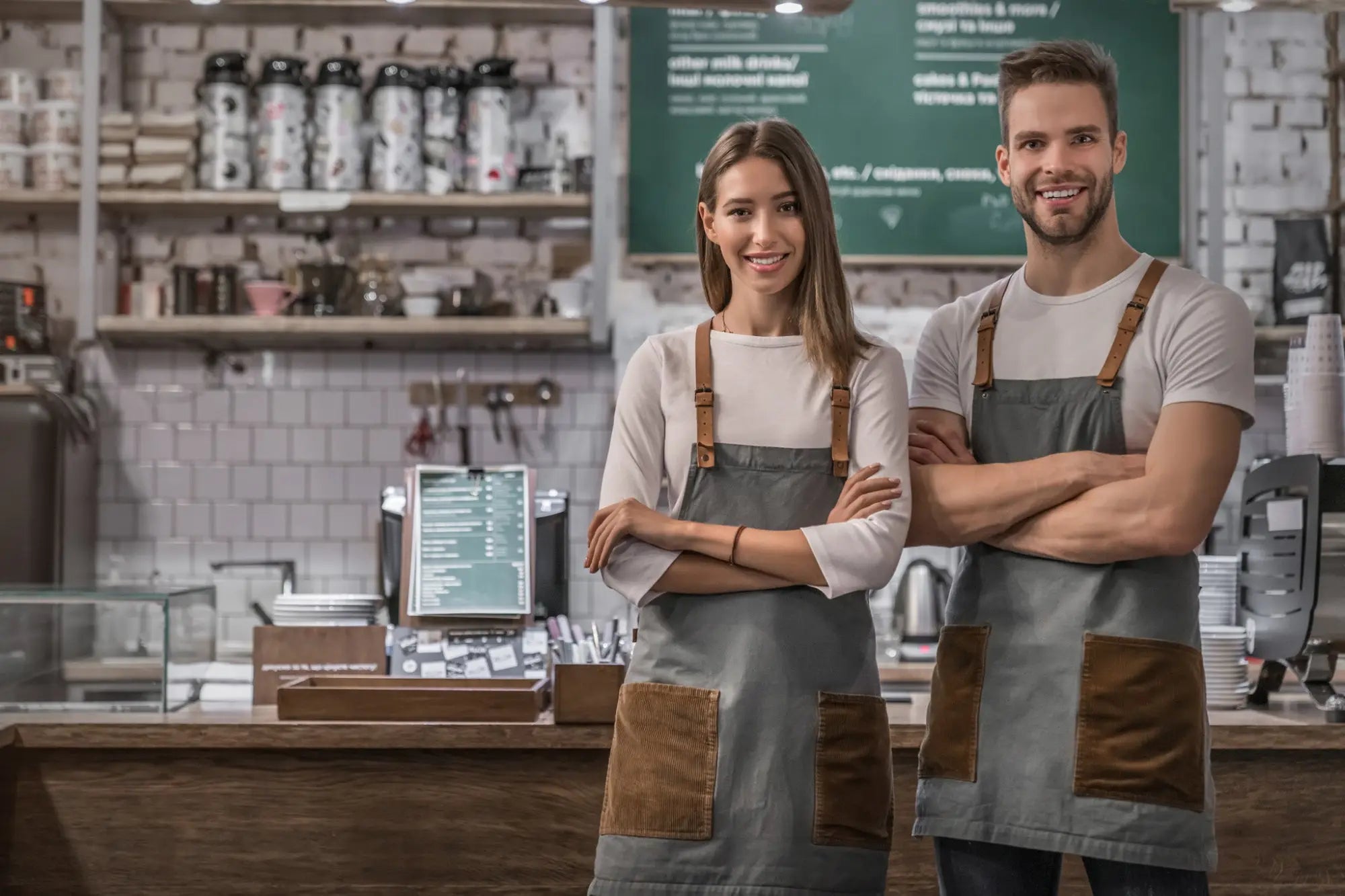 Smiling cafe owners in uniforms showing team spirit boost and brand reinforcement