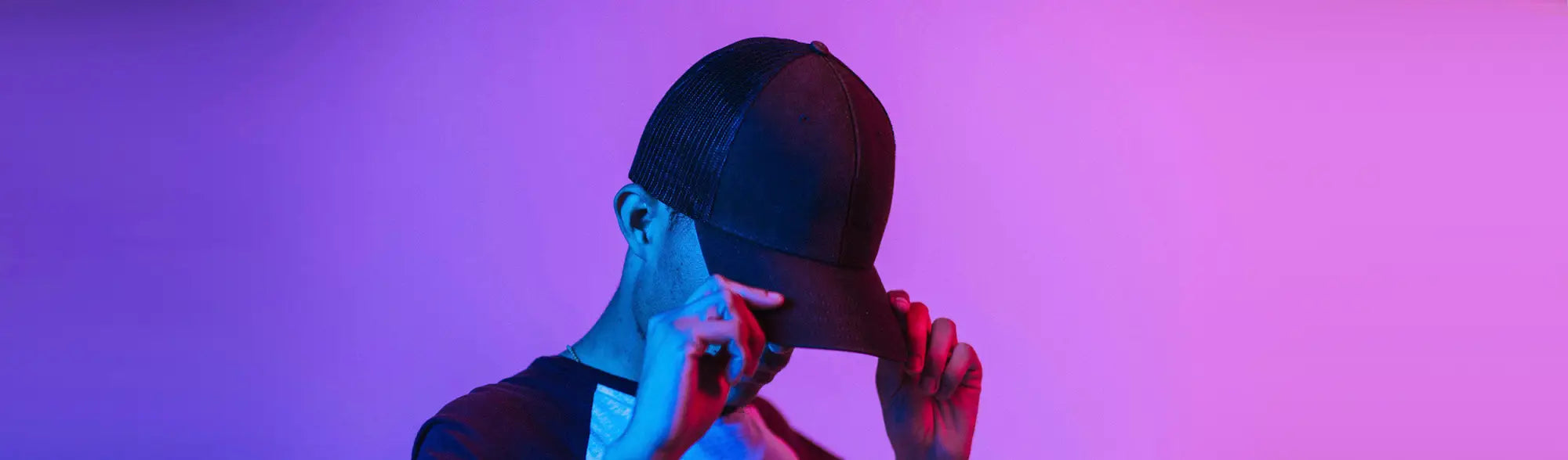 Person adjusting a black baseball cap from the School Hats collection for uniforms or workwear