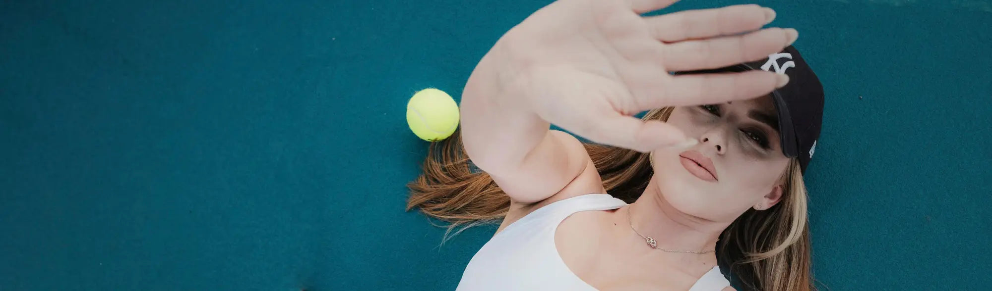 Woman wearing a sports cap holding a tennis ball, perfect for customizable sports caps