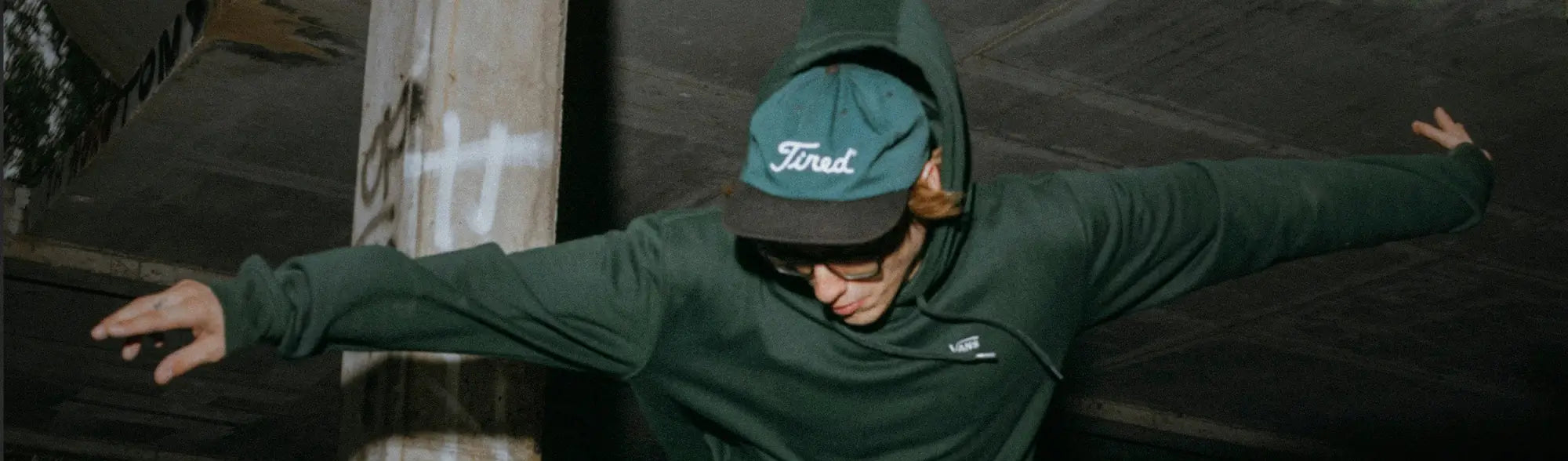 Person in green hoodie and hat wearing unstructured caps for casual workwear or uniforms