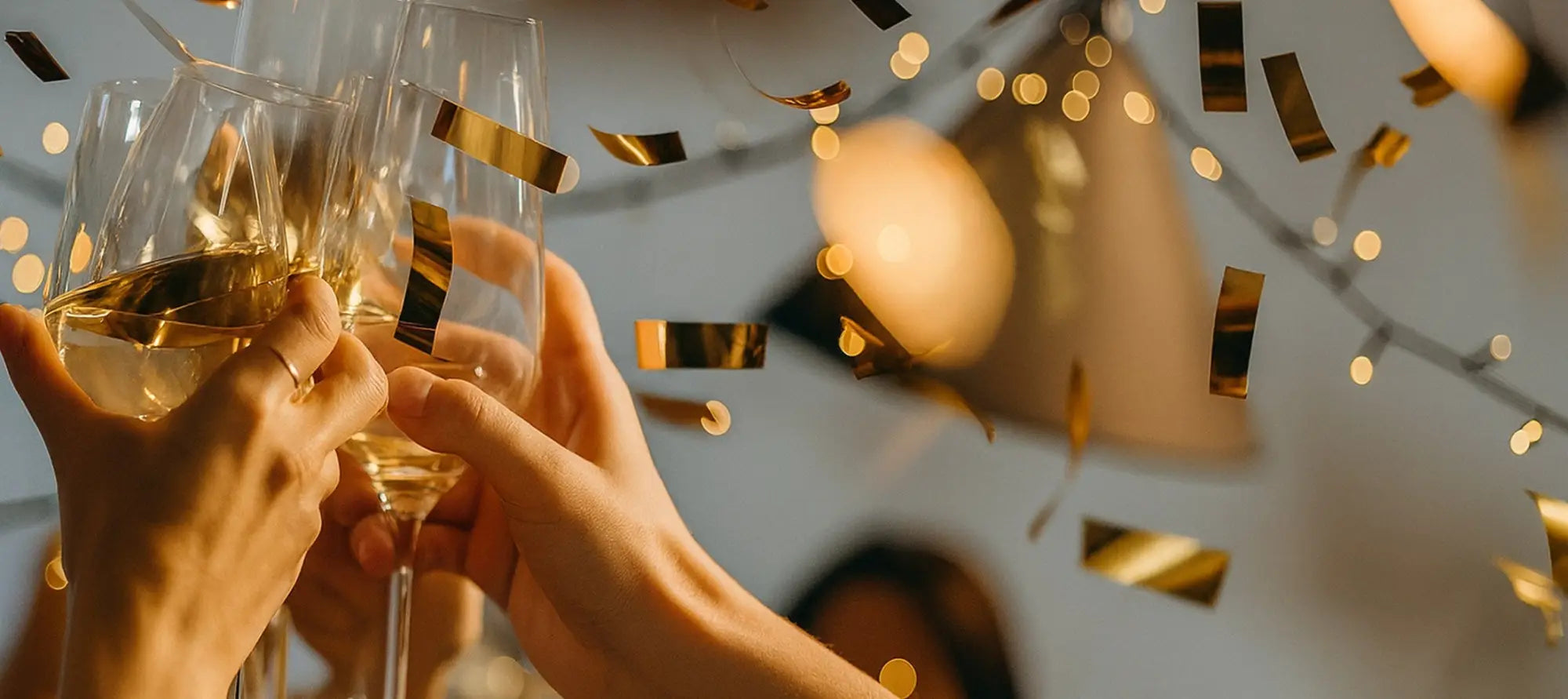 Hands holding champagne flutes with confetti for Let’s Celebrate work uniforms party scene