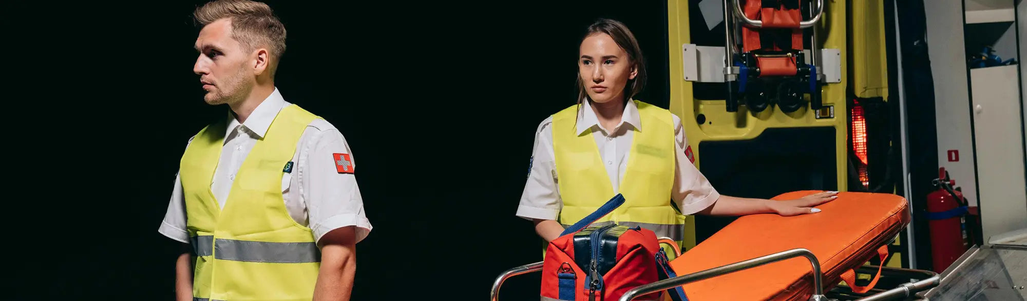 Paramedics with ambulance stretcher wearing PPE safety vests for maximum visibility