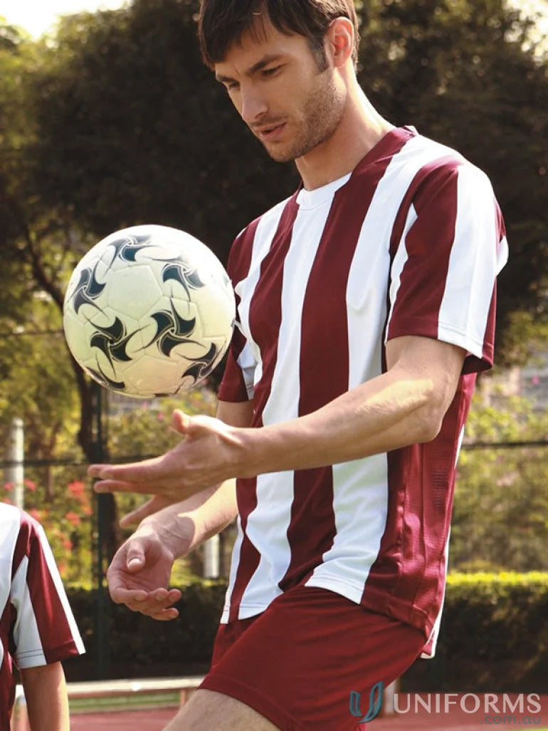 Male soccer player in striped football jersey juggling a football on field