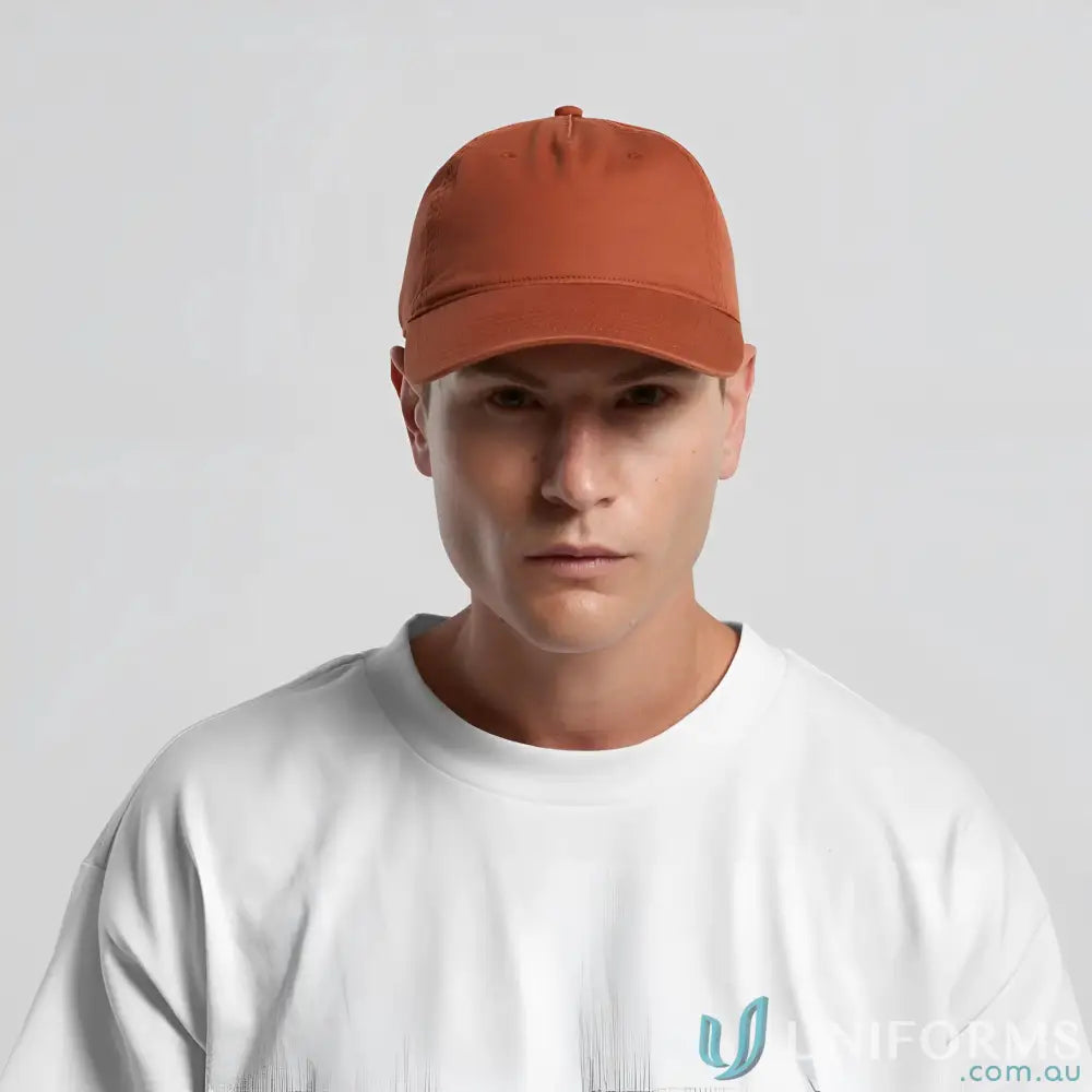 Man wearing a rust-colored baseball cap with curved peak and adjustable metal clasp