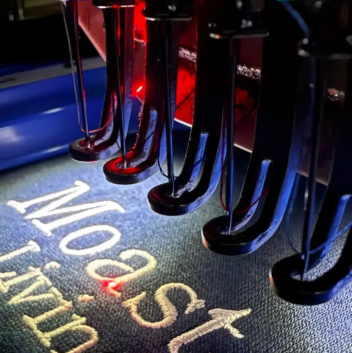 BRD: EMBROIDERY Position black machine with red blue lights stitching onsite embroidery