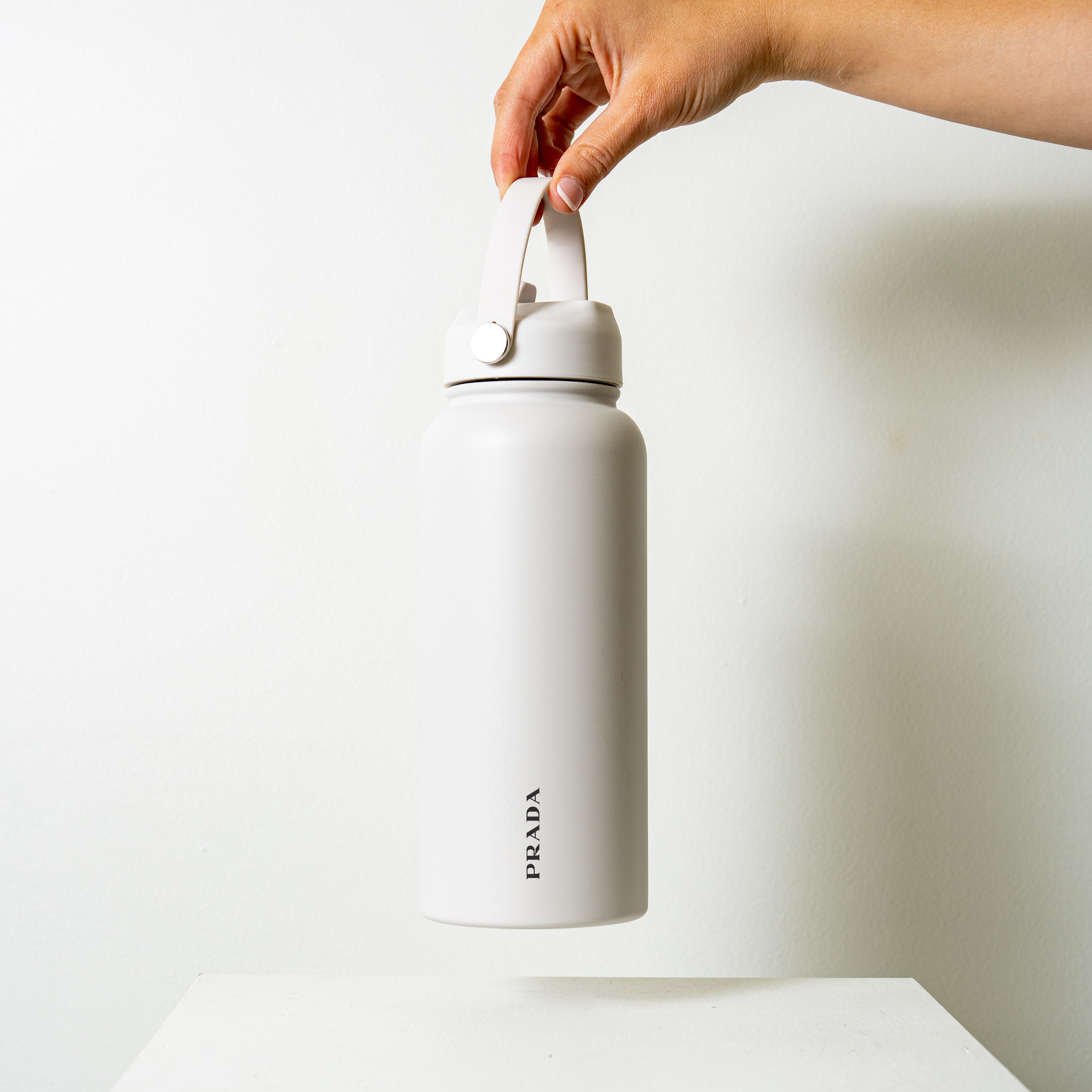 White Prada 1L insulated stainless steel bottle with silver lid, integrated carry handle and stainless steel straw