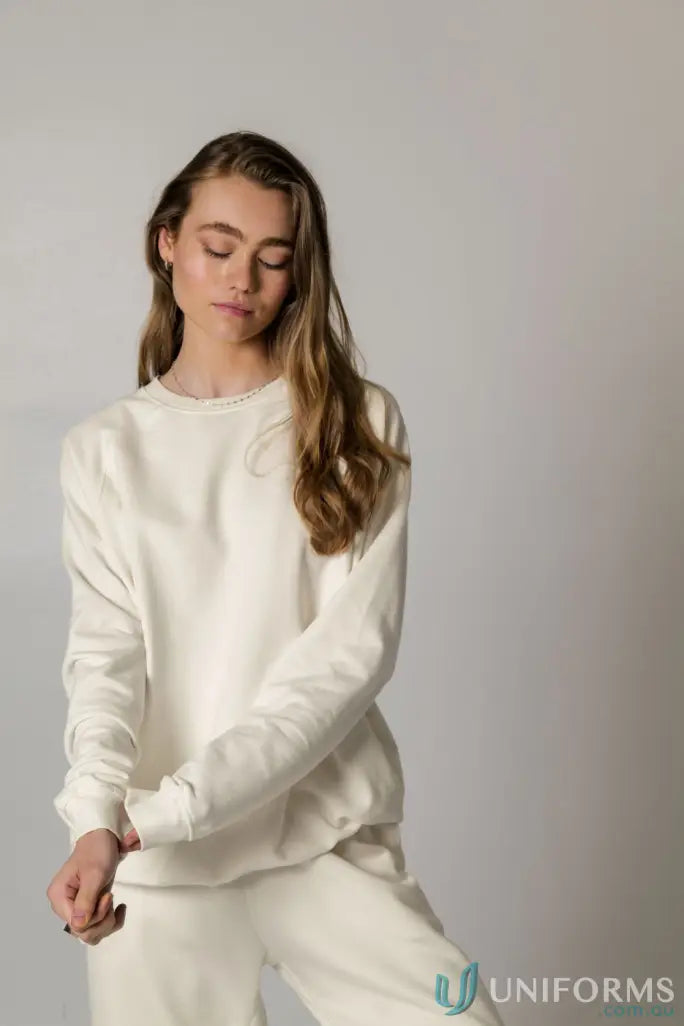 Woman wearing a matching cream-colored Archie Crew Sweat and sweatpants outfit