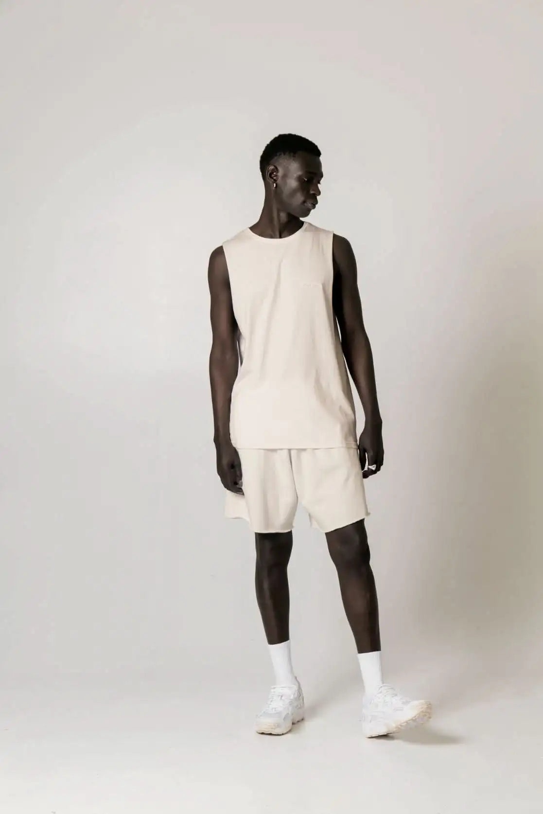 Man in beige Cotton Tank Top with raw cut sleeve and nameless chest embroidery