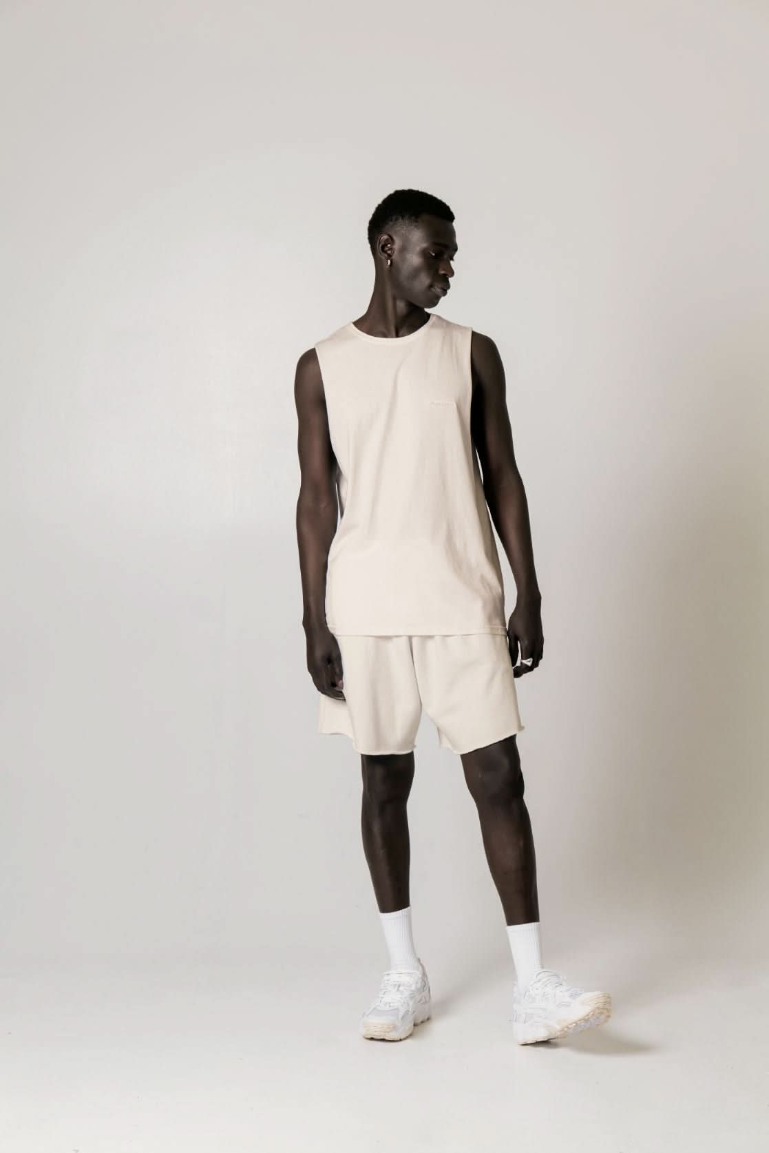 Man in beige Cotton Tank Top with raw cut sleeve and nameless chest embroidery