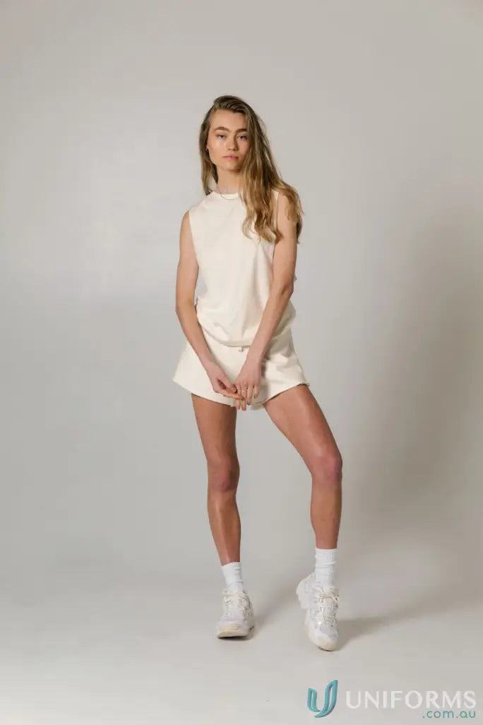 Woman in cream-colored Cotton Tank Top with raw cut sleeve and nameless chest embroidery
