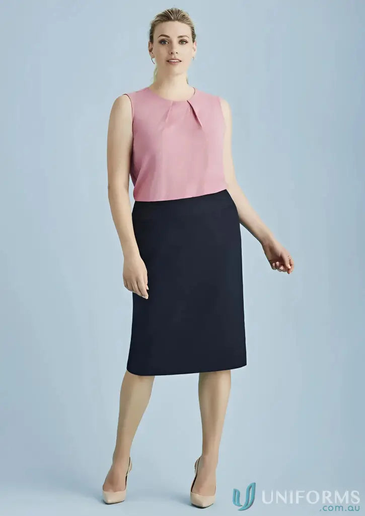 Woman modeling pink sleeveless top and navy blue skirt as stylish workwear uniform