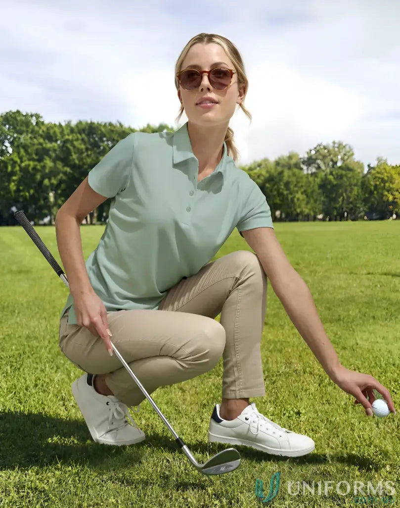 Woman golfing in ladies sustainable jacquard knit polo shirt in khaki pants