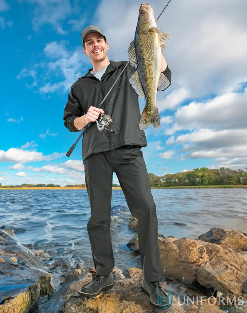 Smiling fisherman with walleye wearing lightweight nylon waterproof rain pants for rainy days