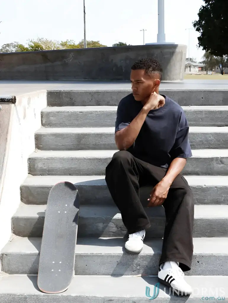 Skateboarder relaxing on concrete steps wearing Luxe Oversized Tee with oversized fit