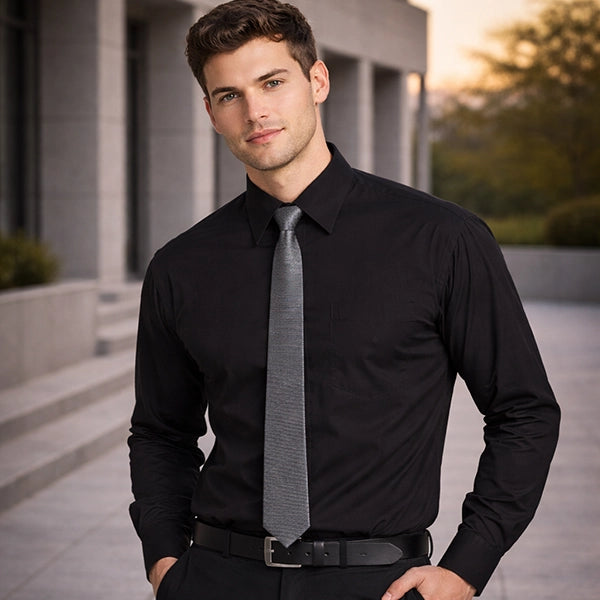 Man wearing a black dress shirt and gray tie standing outdoors.