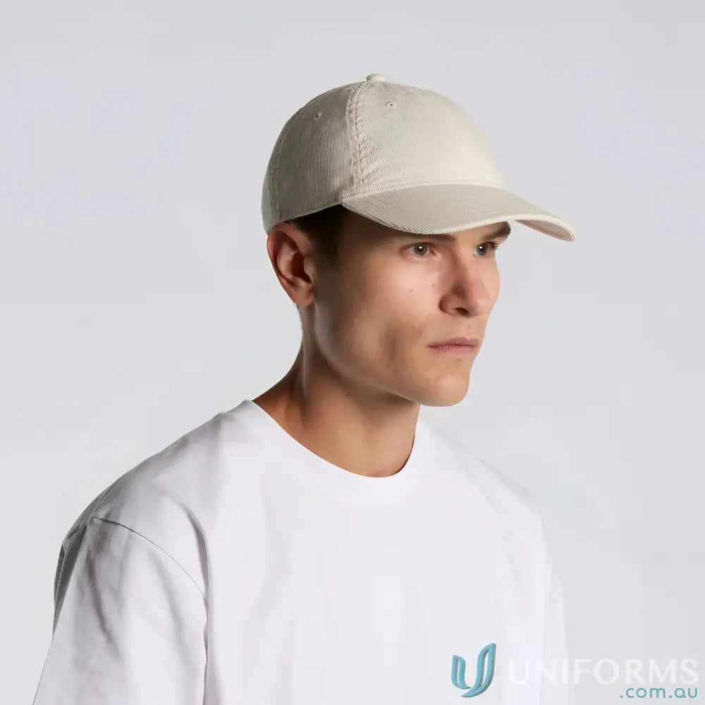 A man wears a light beige cotton 16-wale Partridge access cord cap with adjustable fastener