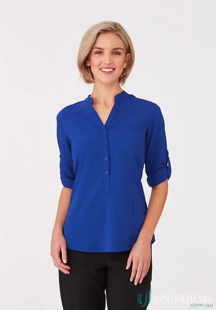 Woman in royal blue SoEzy Top workwear with roll-up sleeves and black trousers