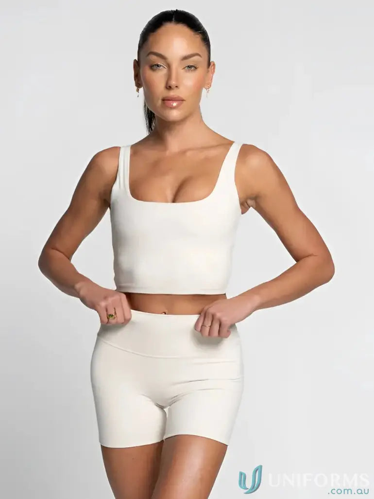 Woman in off-white square neck tank with shelf bra, matching athletic top and shorts
