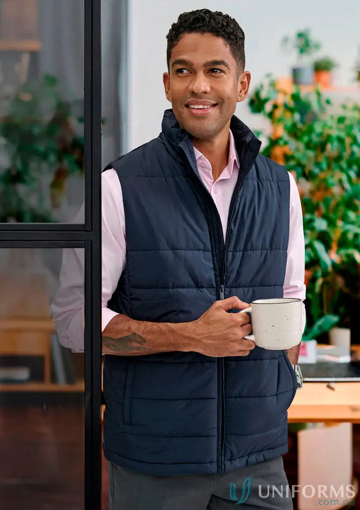 Man in navy blue sustainable insulated puffer vest made from recycled PET bottles holding a mug