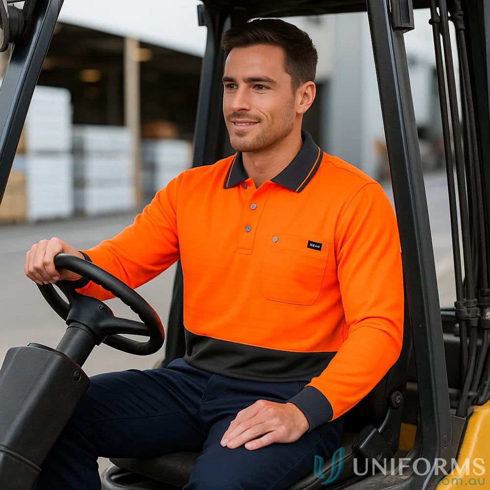 Smiling man in Syzmik Men’s high visibility long sleeve polo operating forklift