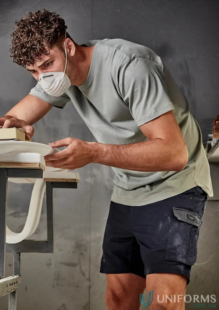 Man sanding a surfboard wearing Syzmic Rugged Cooling Stretch Shorts, perfect work shorts