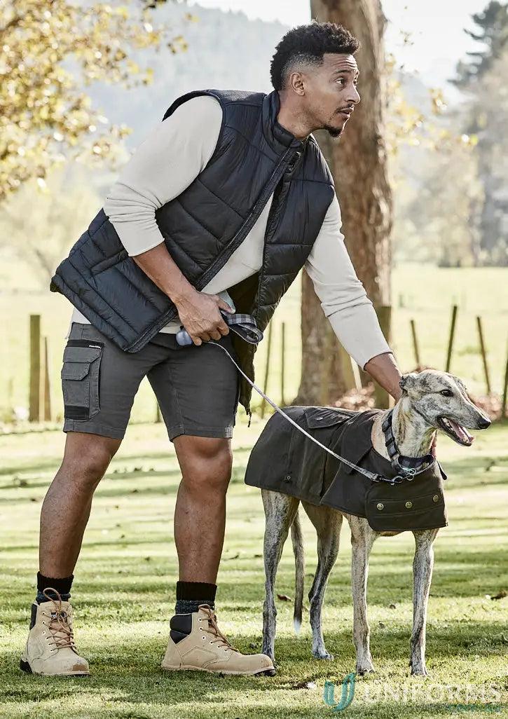 Man in streetworx heritage work shorts with mobile phone pocket walking dog in coat
