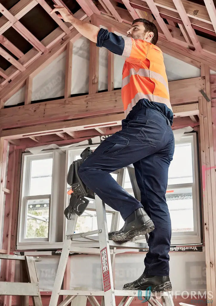 Man in workwear on ladder wearing Syzmik Men’s Summer Cargo Pant for long summer shifts and staying cool