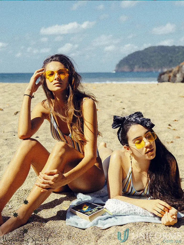 Two women in swimsuits with a spirit terry velour beach towel at the beach