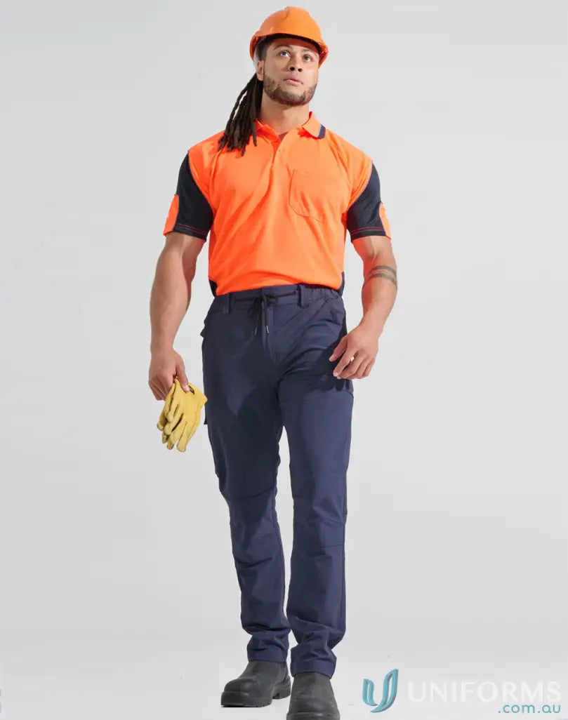 Man in orange flexi work pants with water repellent DWR finish holding yellow gloves