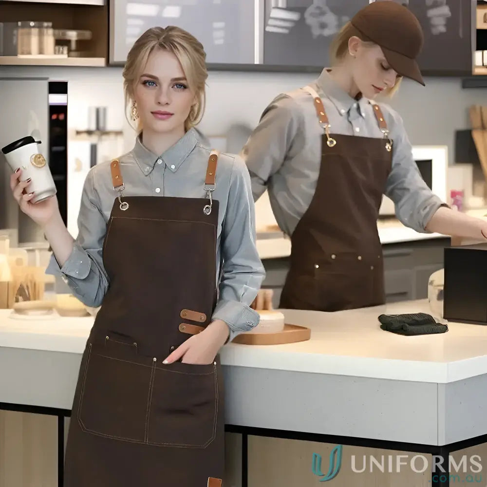 Two people wearing matching waterproof canvas kitchen aprons with leather straps in eight vibrant colours