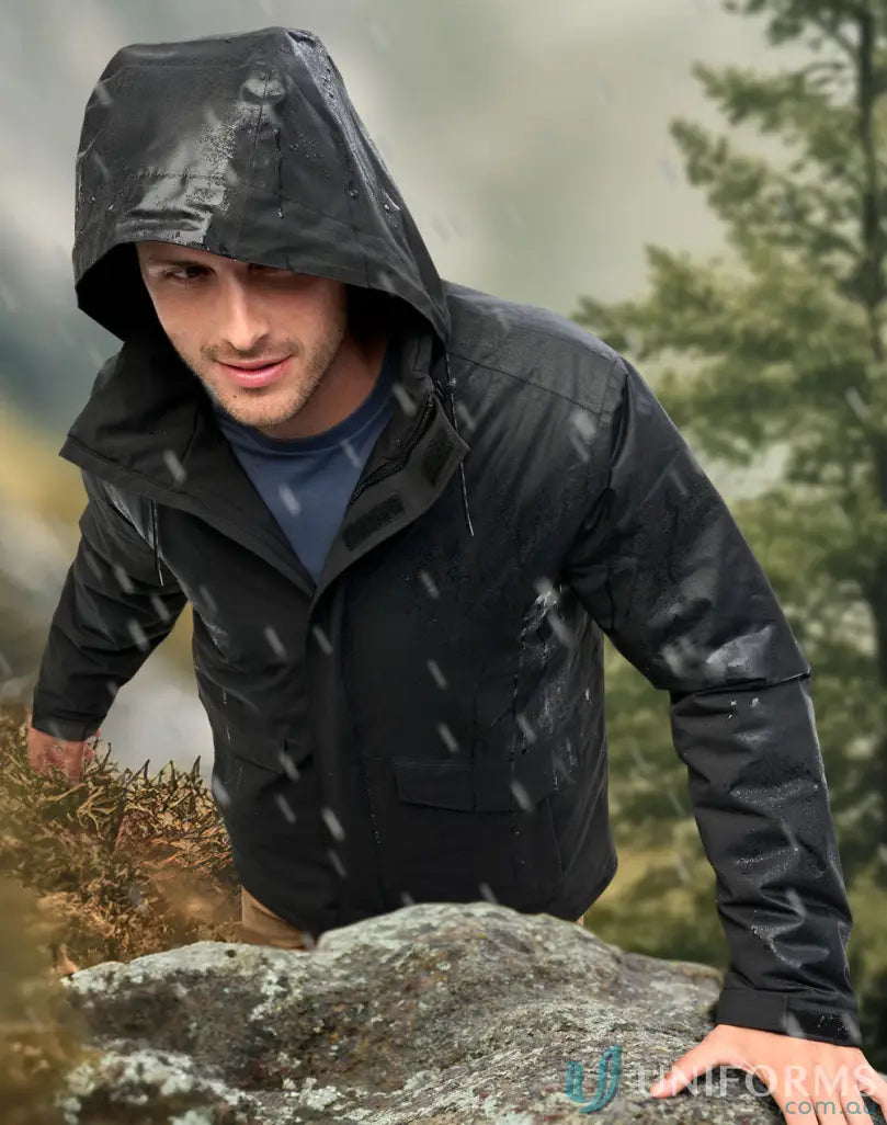 Man in waterproof quilted jacket climbing rocky terrain in light snow, stay dry workwear
