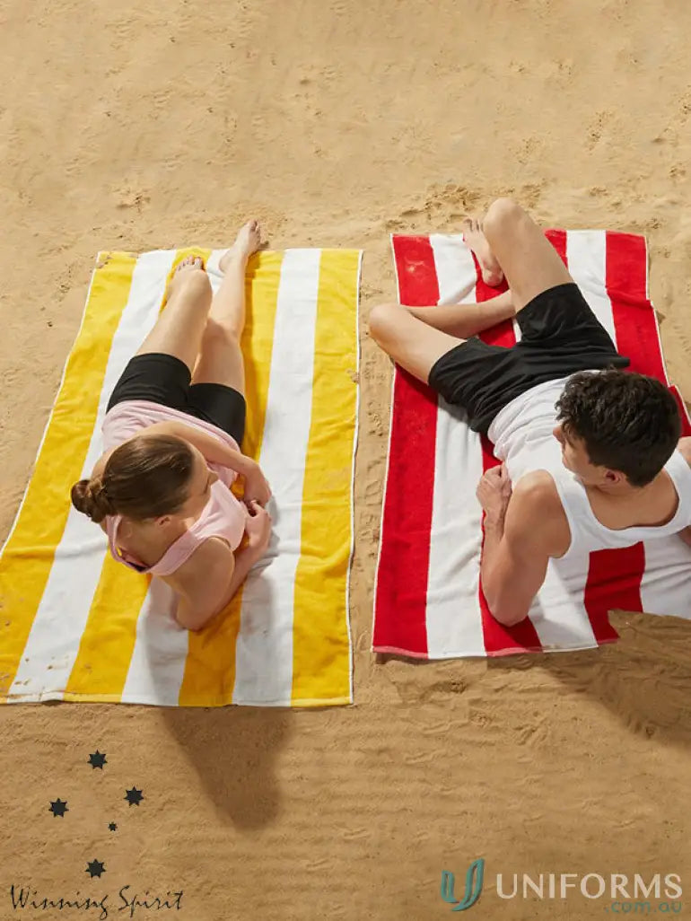 Beachgoers relaxing on a Winning Spirit striped beach towel made of soft terry towelling