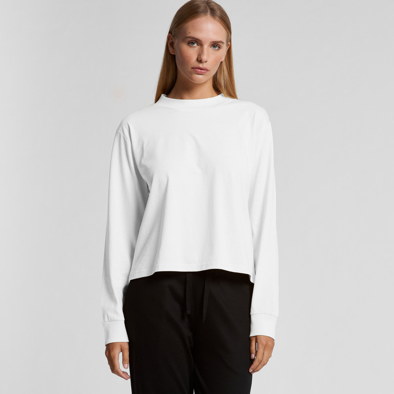 White long-sleeved crew neck top with black pants.