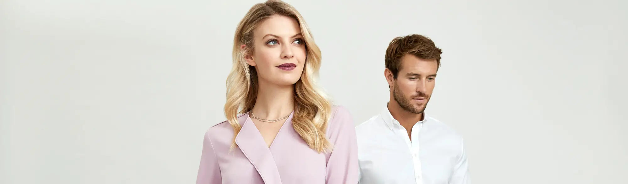 Blonde woman and brown-haired man smiling, showcasing automated uniform ordering for staff uniforms in multi-location businesses