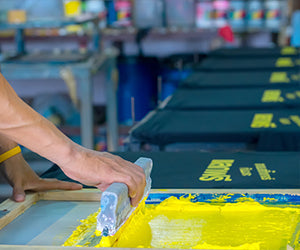 Manual screen printing press with squeegee and yellow ink for affordable screen printing prices
