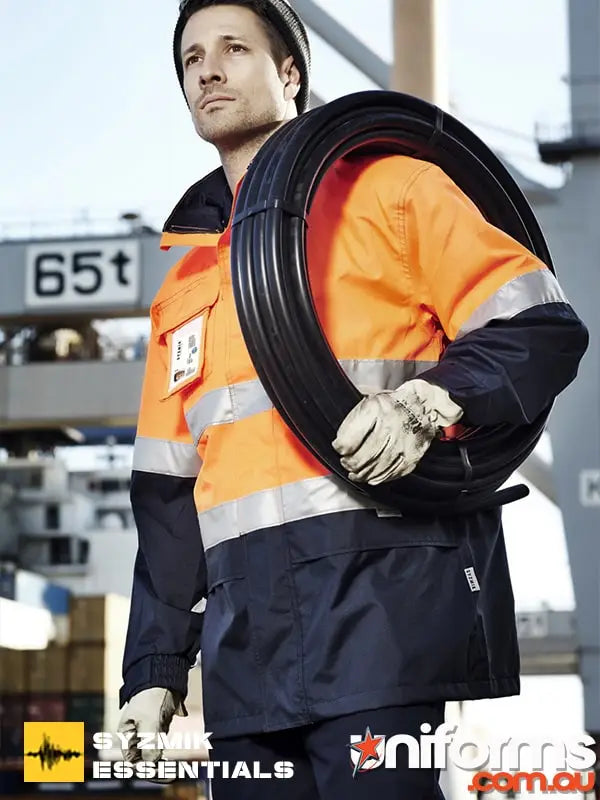 Man in orange and navy Syzmik Workwear carrying black tubing for modern Aussie workplaces