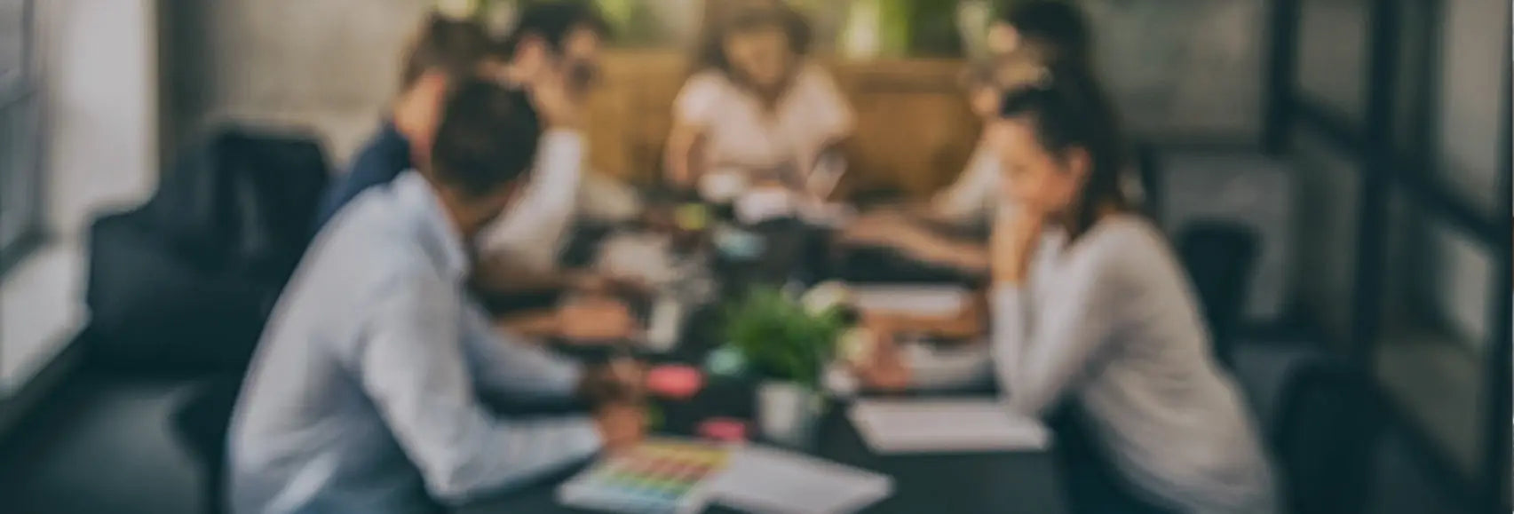 Blurred image of people in work uniforms gathered around a table for a meeting