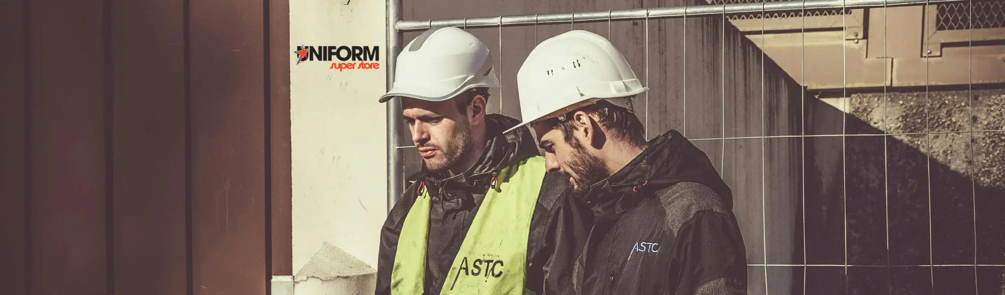 Two construction workers in hard hats wearing disposable protective workwear for maximum safety