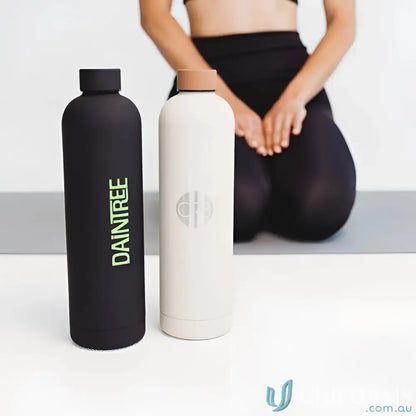 Two stainless steel Allegra 1L insulated bottles in car cup holders, double-wall vacuum design