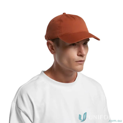 Person wearing a burnt orange baseball cap with curved peak and adjustable metal clasp