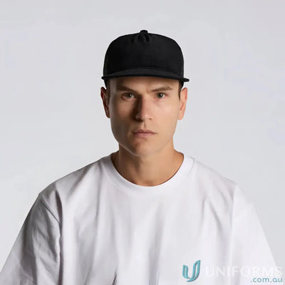 Man wearing black flat peak AS Colour Class Cord Trucker Cap in cotton 16-wale partridge