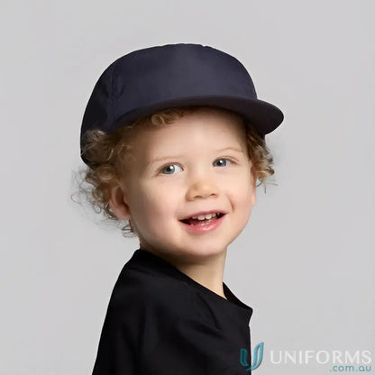 Cute kid with curly hair wearing AS Colour Kids Surf Cap 1129 with soft foam peak