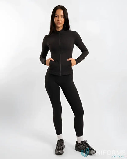Woman in black athletic wear showing off the Contour Zip Jacket with high neck collar