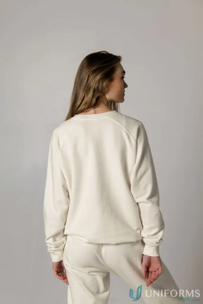 Woman in a cream-colored Archie Crew Sweat sweatshirt and sweatpants lounging comfortably