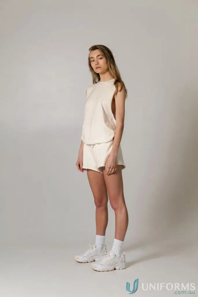 Woman in cream-colored Cotton Tank Top with raw cut sleeve and nameless chest embroidery