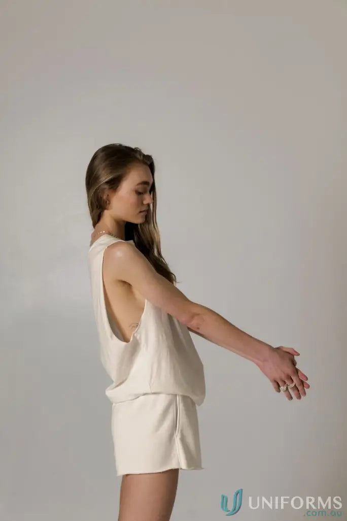 Woman in a cream-colored Cotton Tank Top with raw cut sleeve and nameless chest embroidery